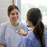 Female doctor hold stethoscope on female patient - Primary Health Care at North Mississippi Primary Health Care